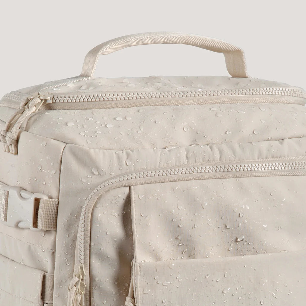 Mochila de viagem Bags Mart na cor Bege — detalhe do tecido, zíperes e alça superior